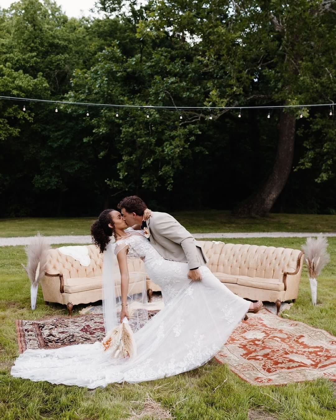 A bride and groom are kissing in front of a couch.