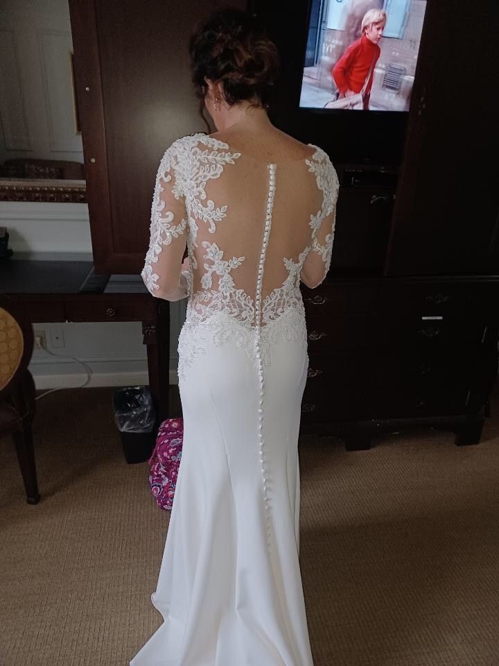 A woman in a white wedding dress is standing in front of a television.