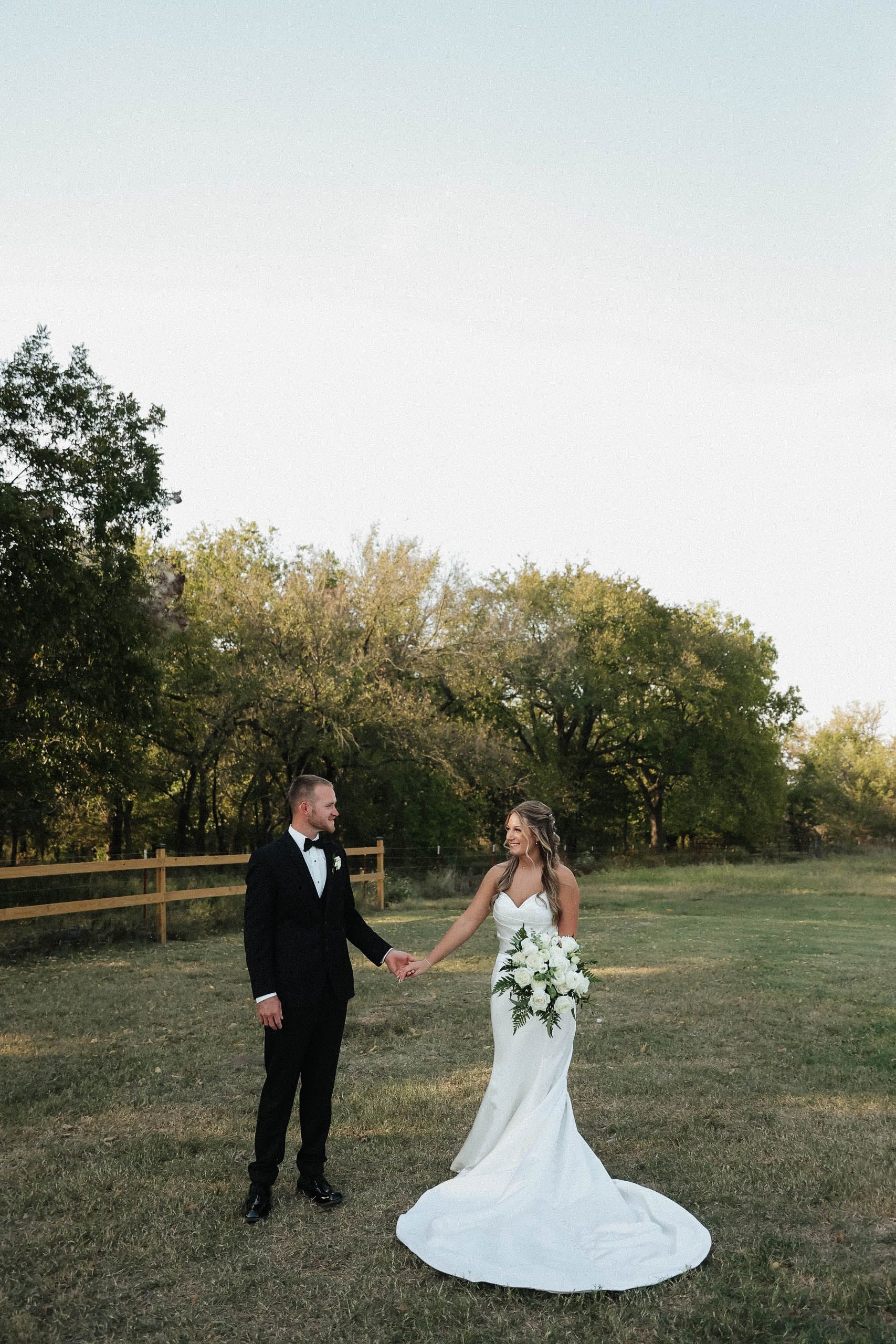 A bride and groom are holding hands in a field.