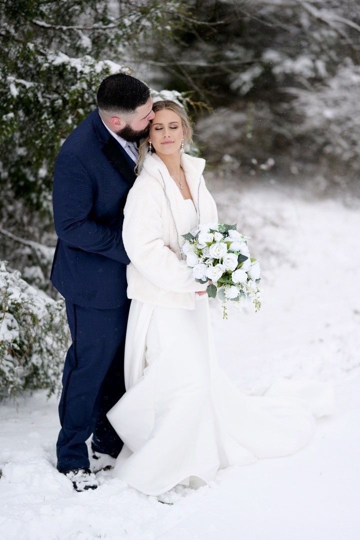 A bride and groom are posing for a picture in the snow.