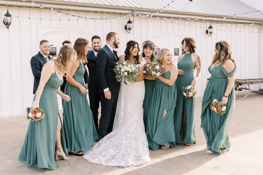 A bride and groom are posing for a picture with their wedding party.