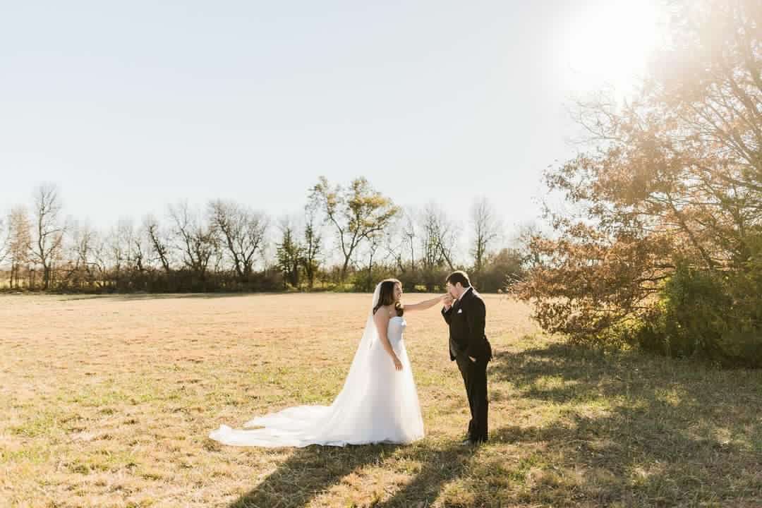 A bride and groom are standing in a field.
