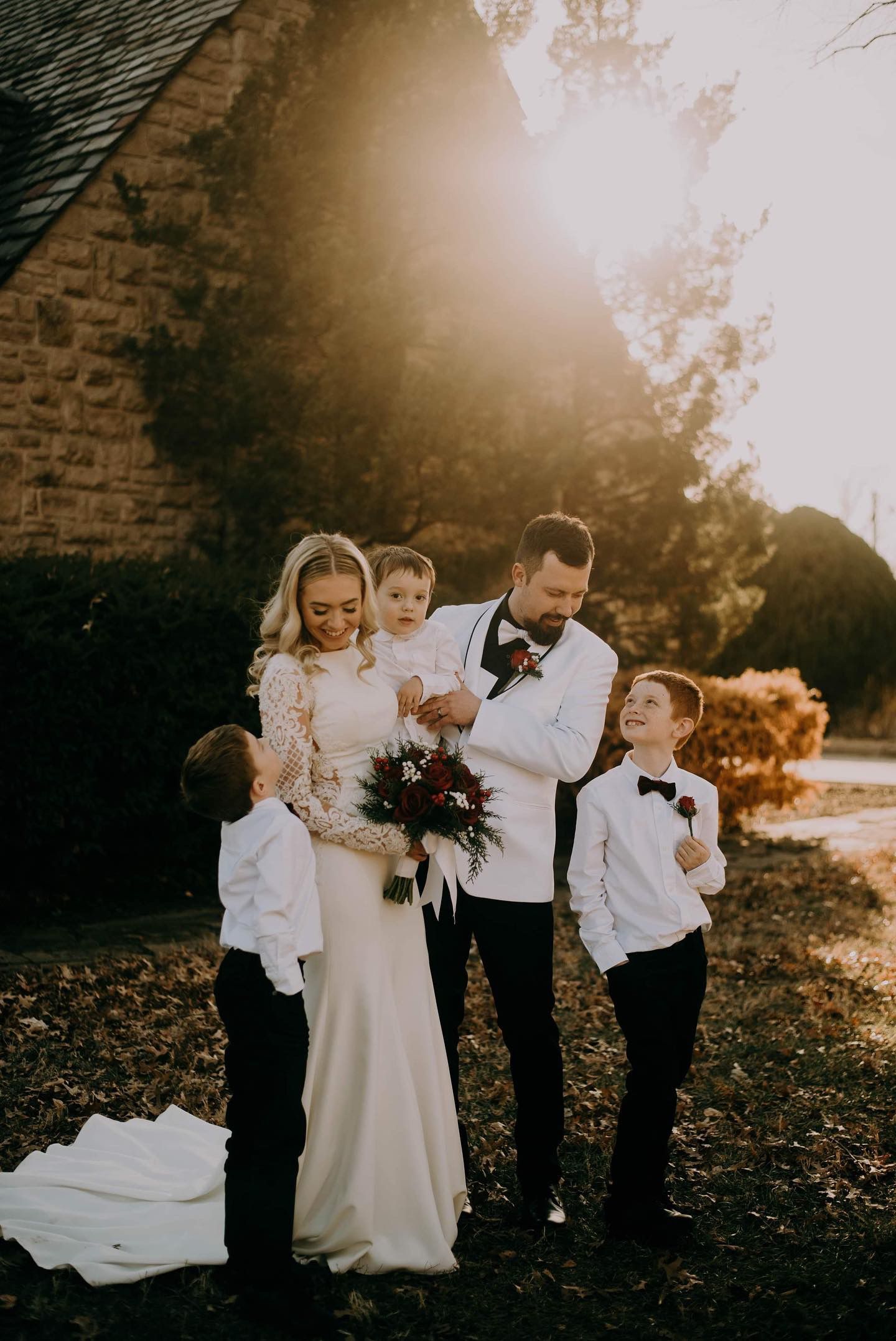 A bride and groom are posing for a picture with their children.