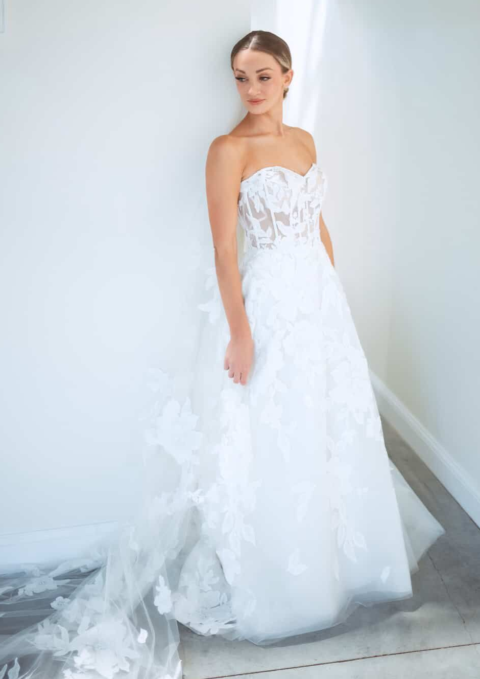 A woman in a white wedding dress is standing in front of a building.