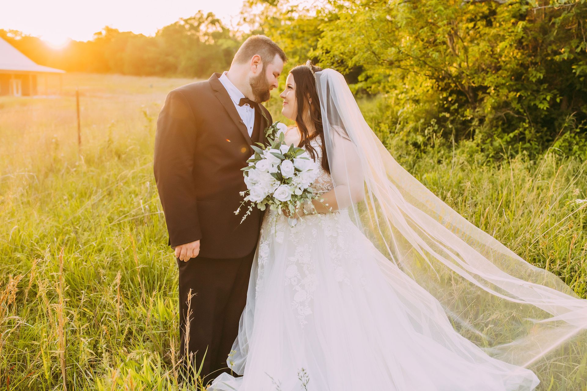 A bride and groom are posing for a picture in a field at their wedding.