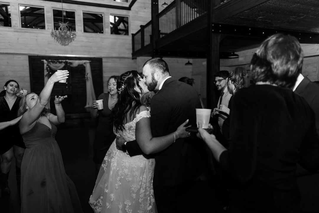 A bride and groom are kissing while dancing at their wedding reception.