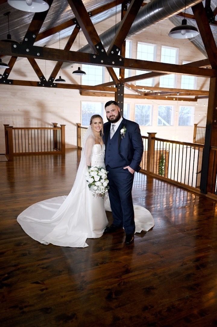 A bride and groom are posing for a picture in a large room.
