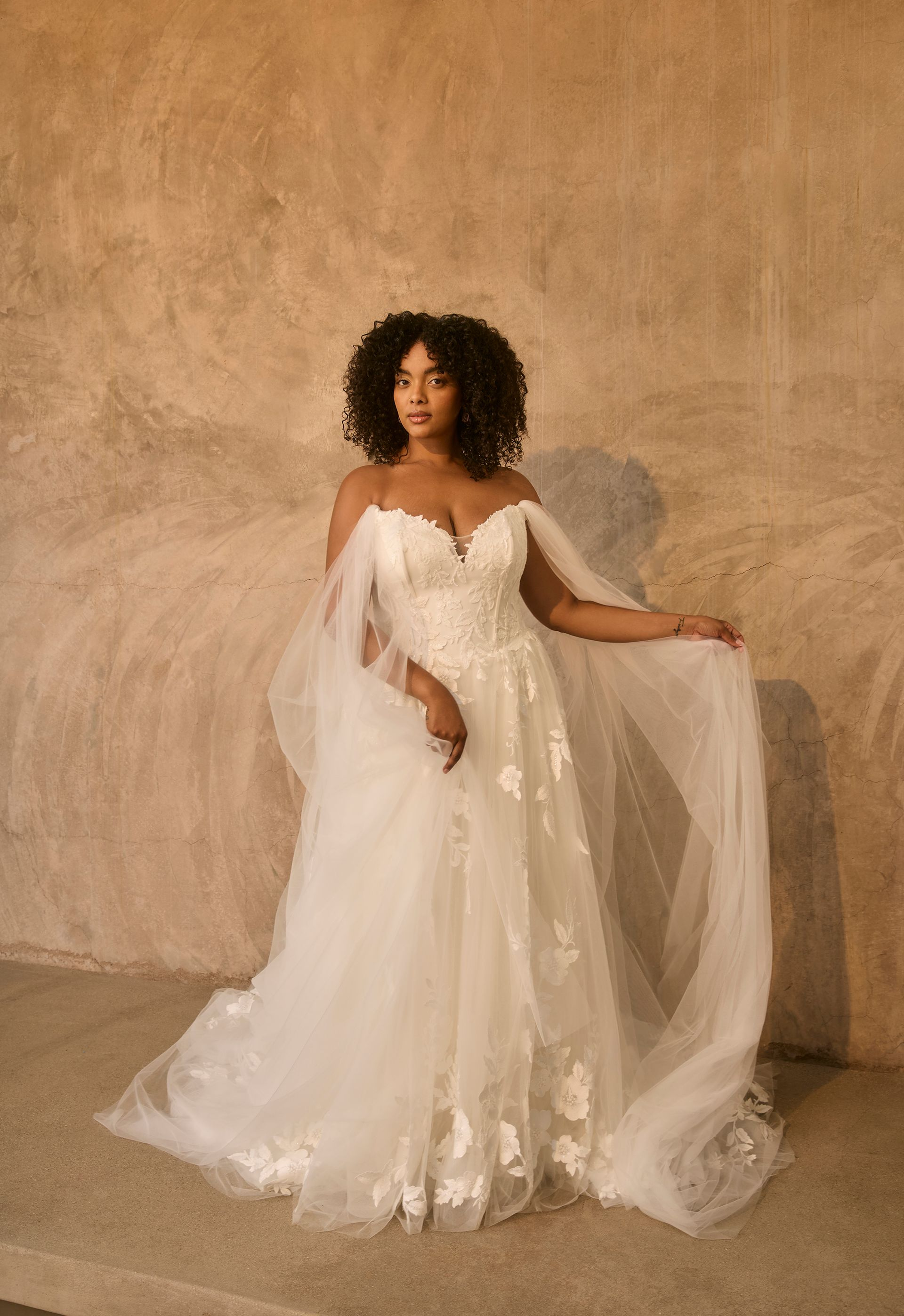 The back of a plus size model wearing a wedding dress with long sleeves.