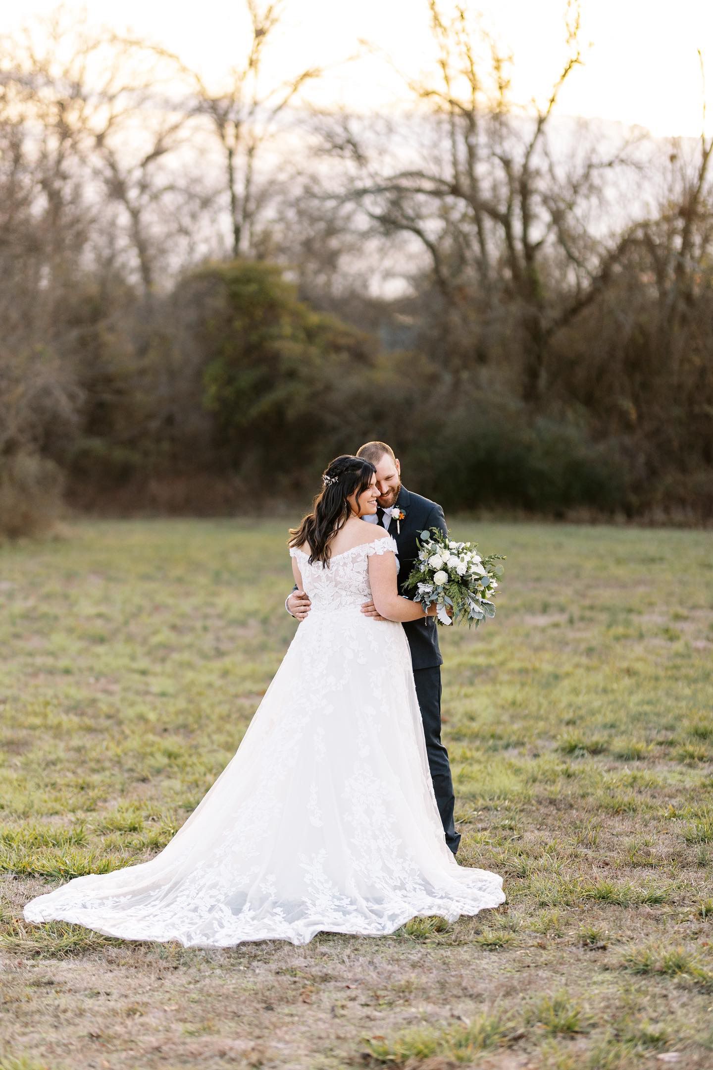 A bride and groom are kissing in a field.