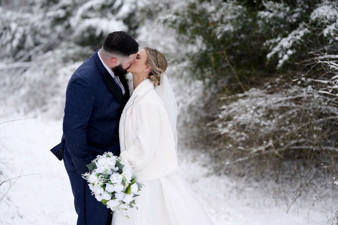 A bride and groom are kissing in the snow.