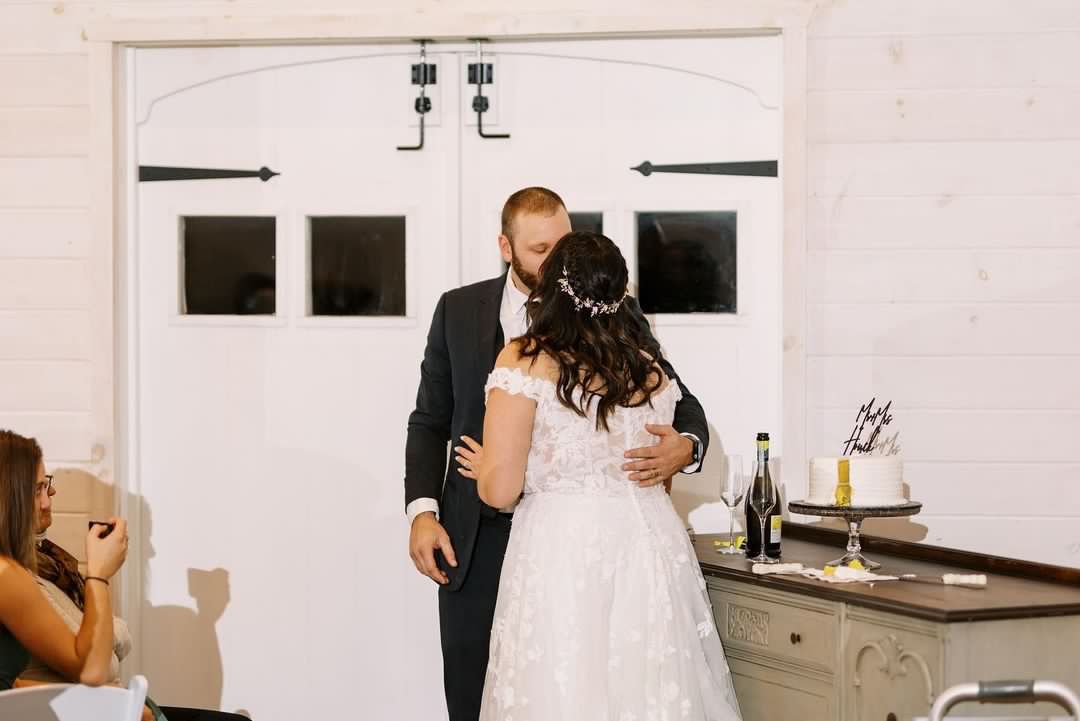 A bride and groom are dancing at their wedding reception in front of a white door.