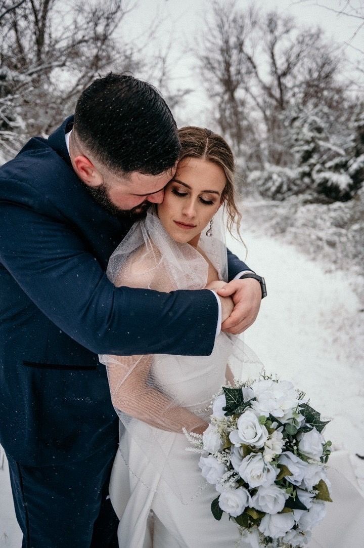 A bride and groom are posing for a picture in the snow.
