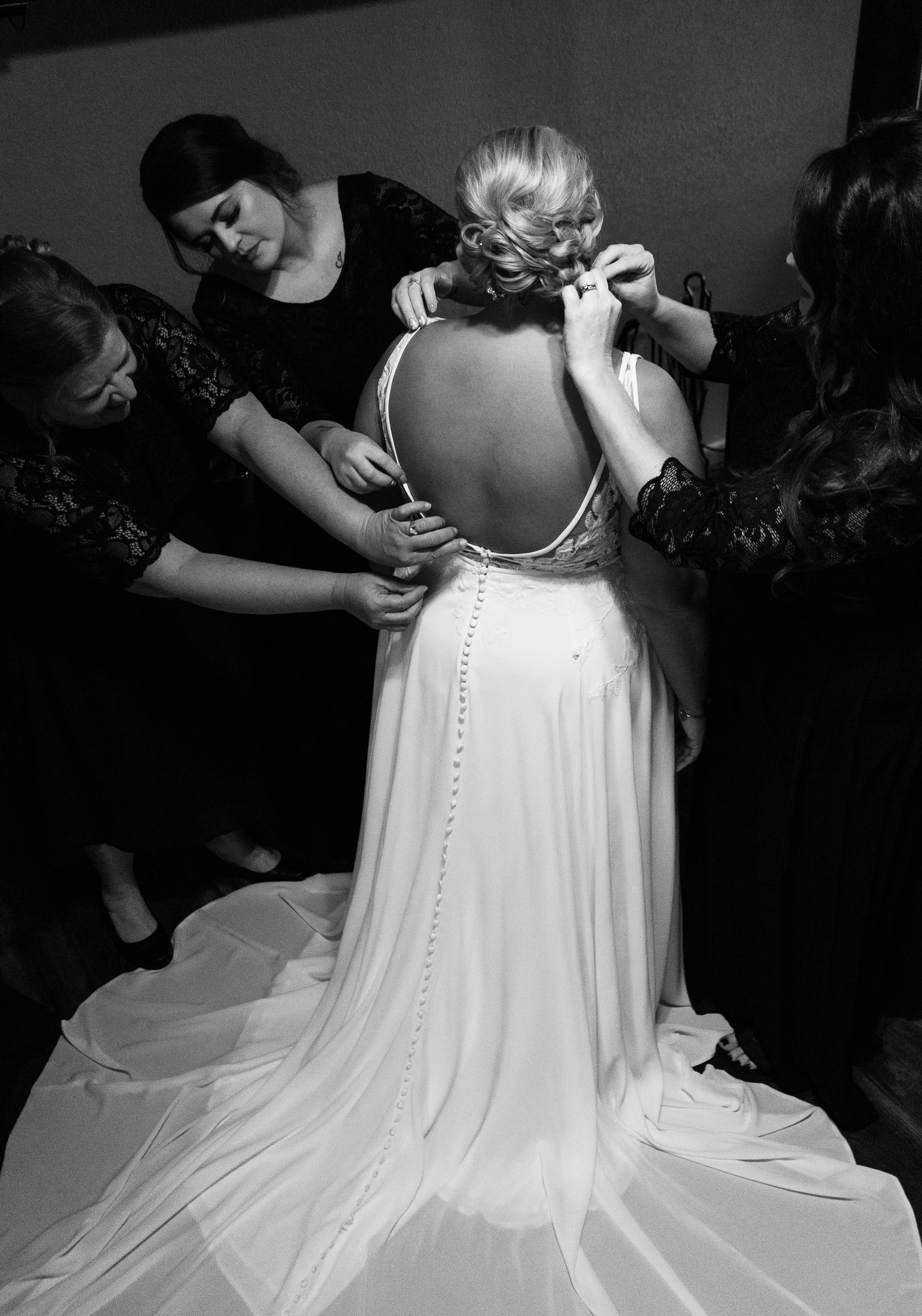 A black and white photo of a woman in a wedding dress getting ready.