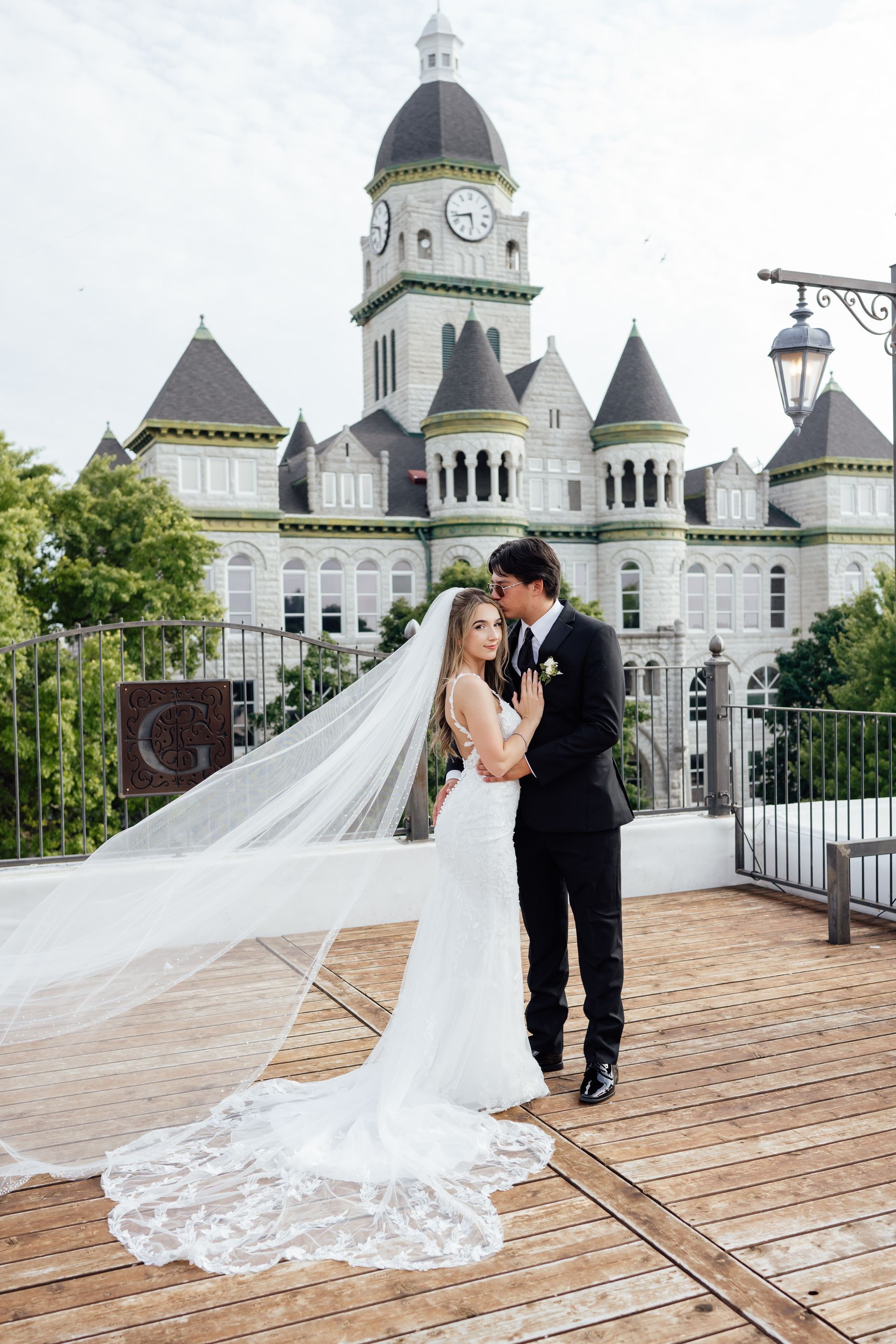 A bride and groom are posing for a picture in front of a large building.