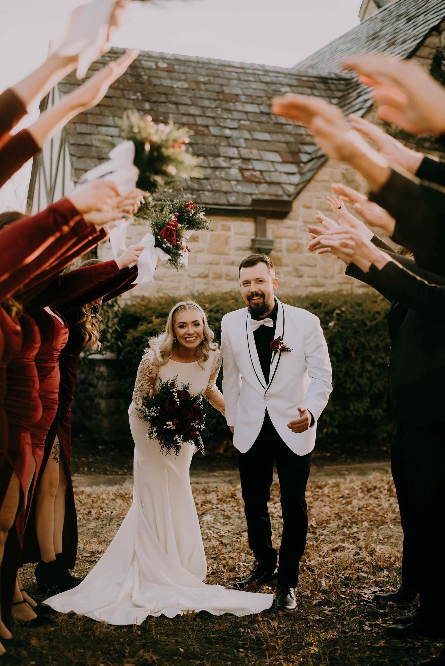A bride and groom are standing in front of a crowd of people throwing confetti at them.