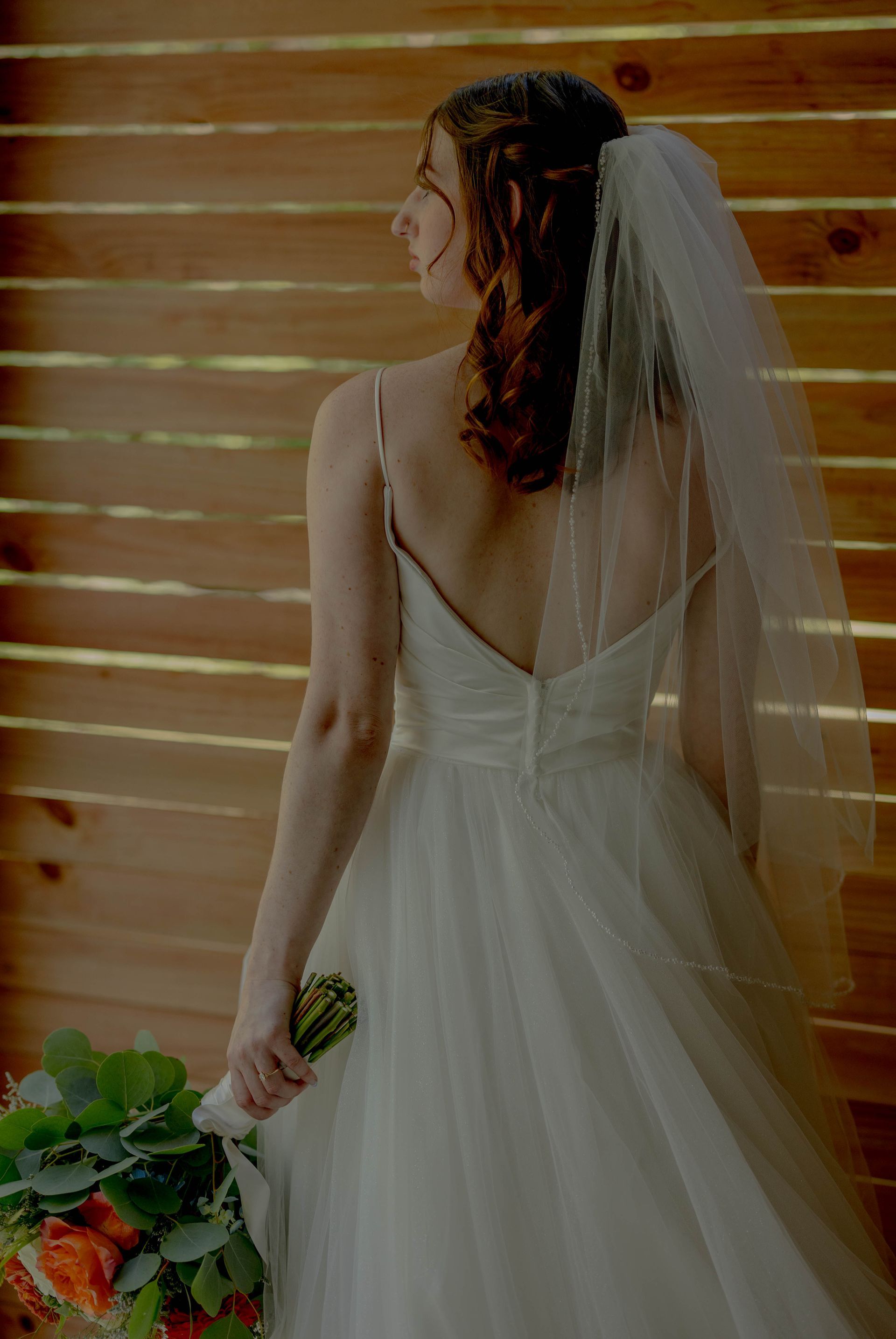 A bride in a wedding dress and veil is holding a bouquet of flowers.