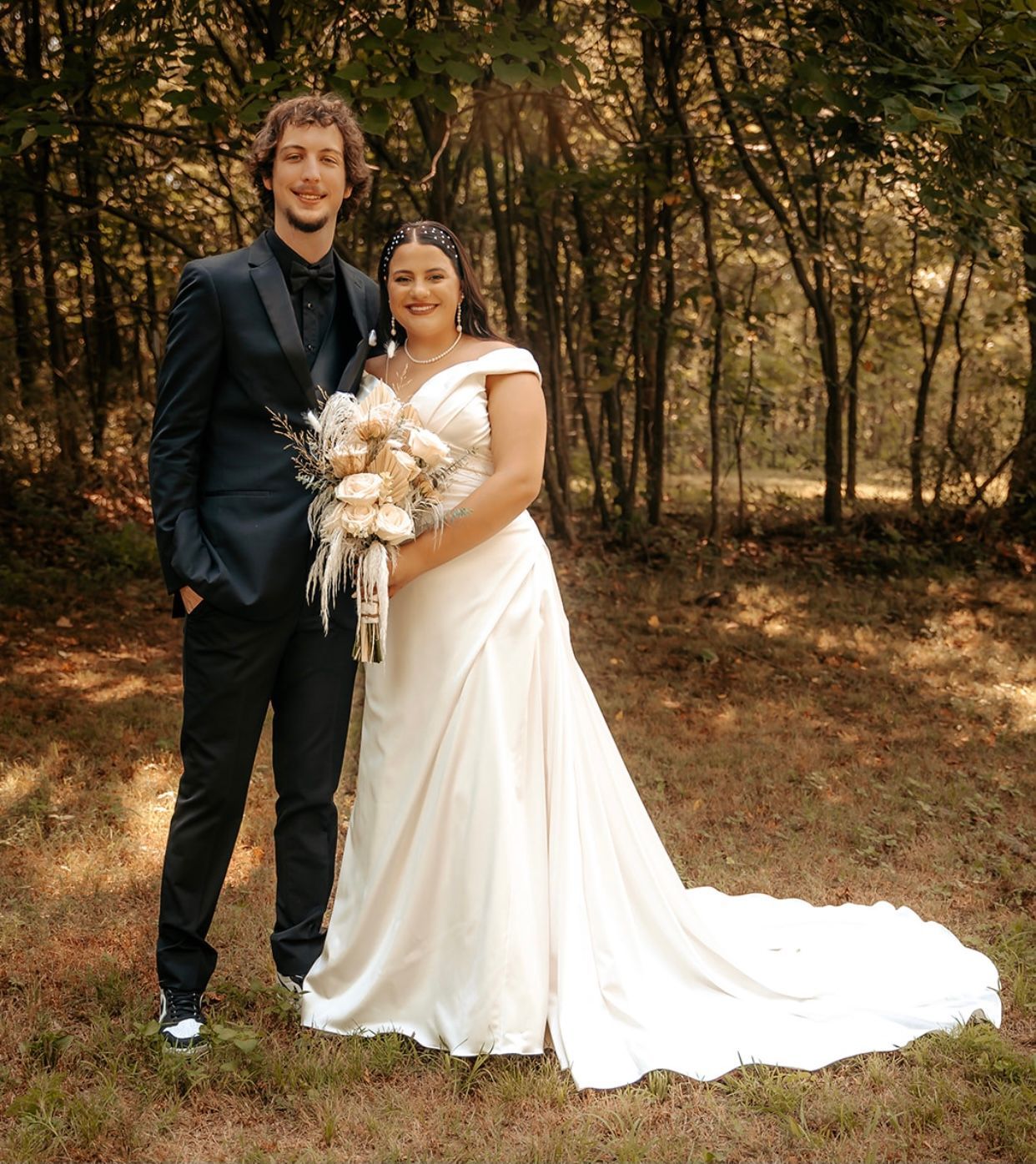 A bride and groom pose for a picture in the woods