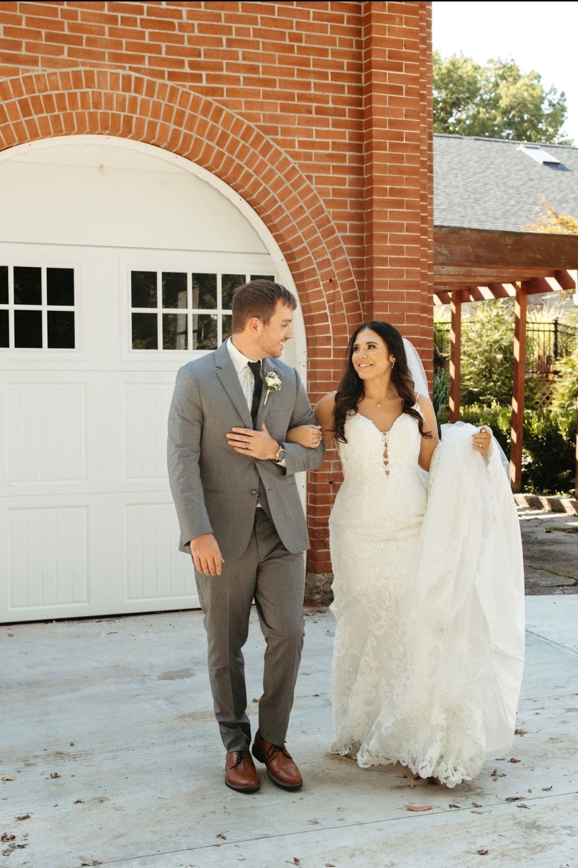 A bride and groom are walking in front of a garage door.