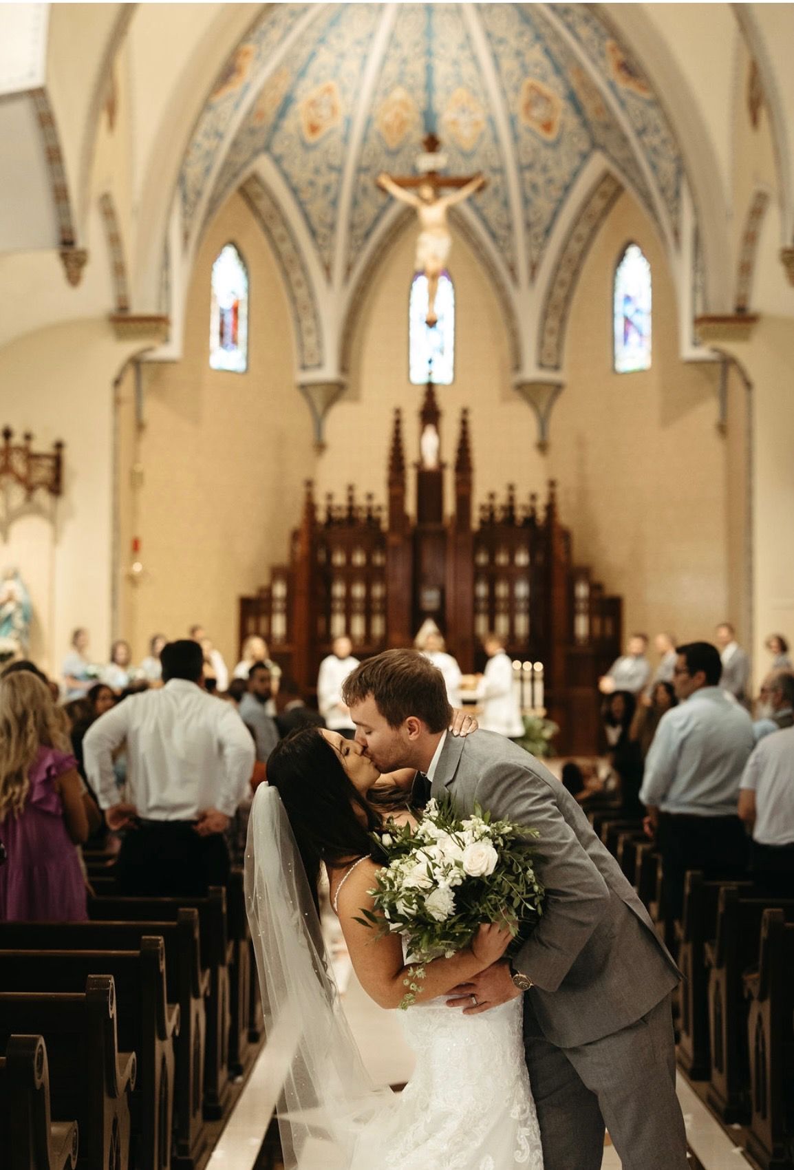 A bride and groom are kissing in a church.