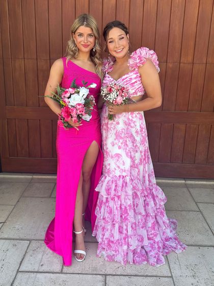Two women are standing next to each other wearing dresses.