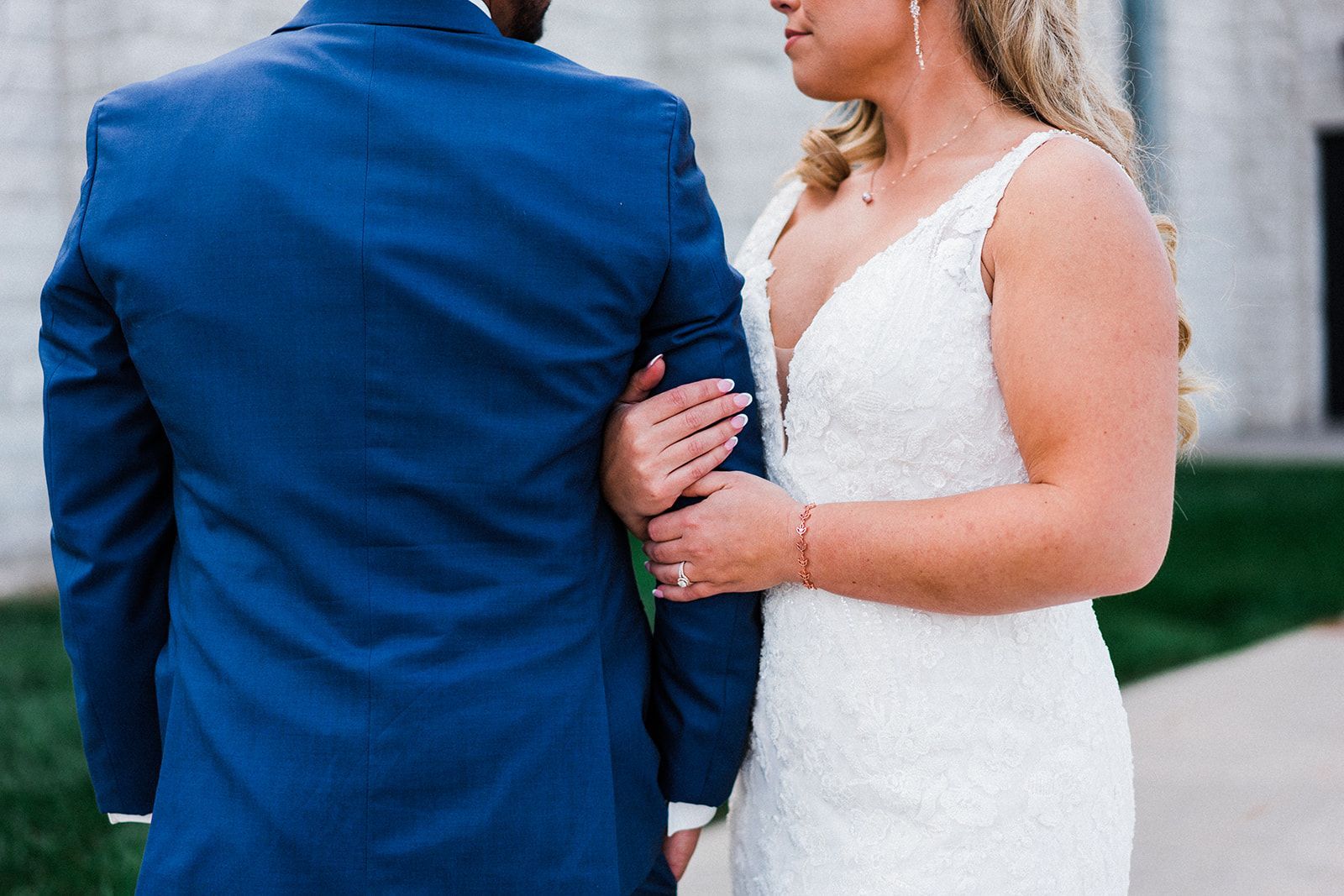 A bride and groom are standing next to each other and holding hands.
