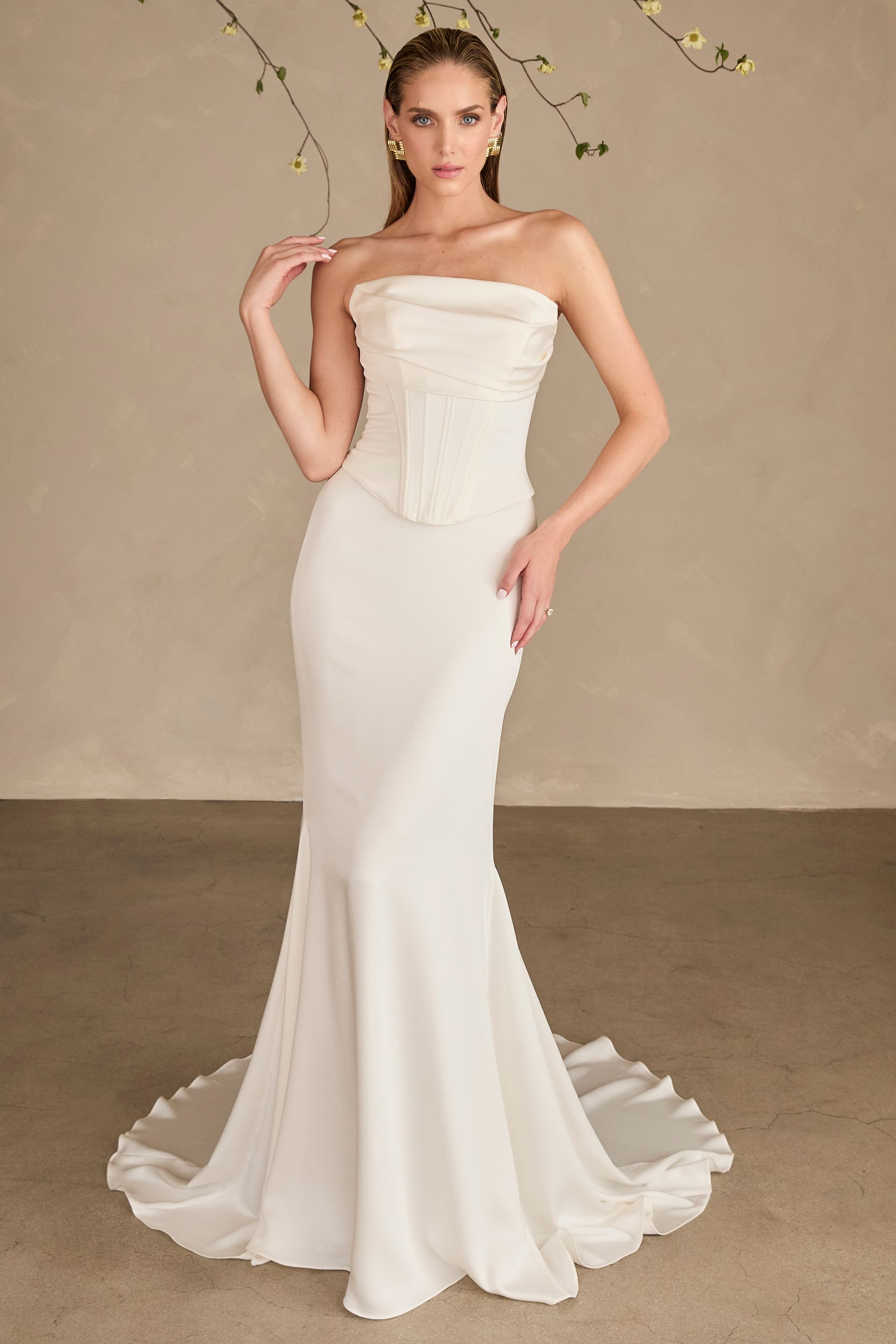 A woman in a white wedding dress is standing in front of a window.