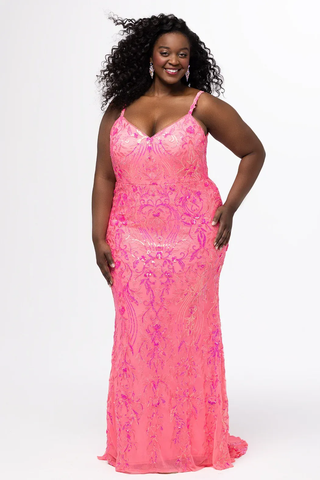 A woman in a white lace dress is standing in front of a green tiled wall.