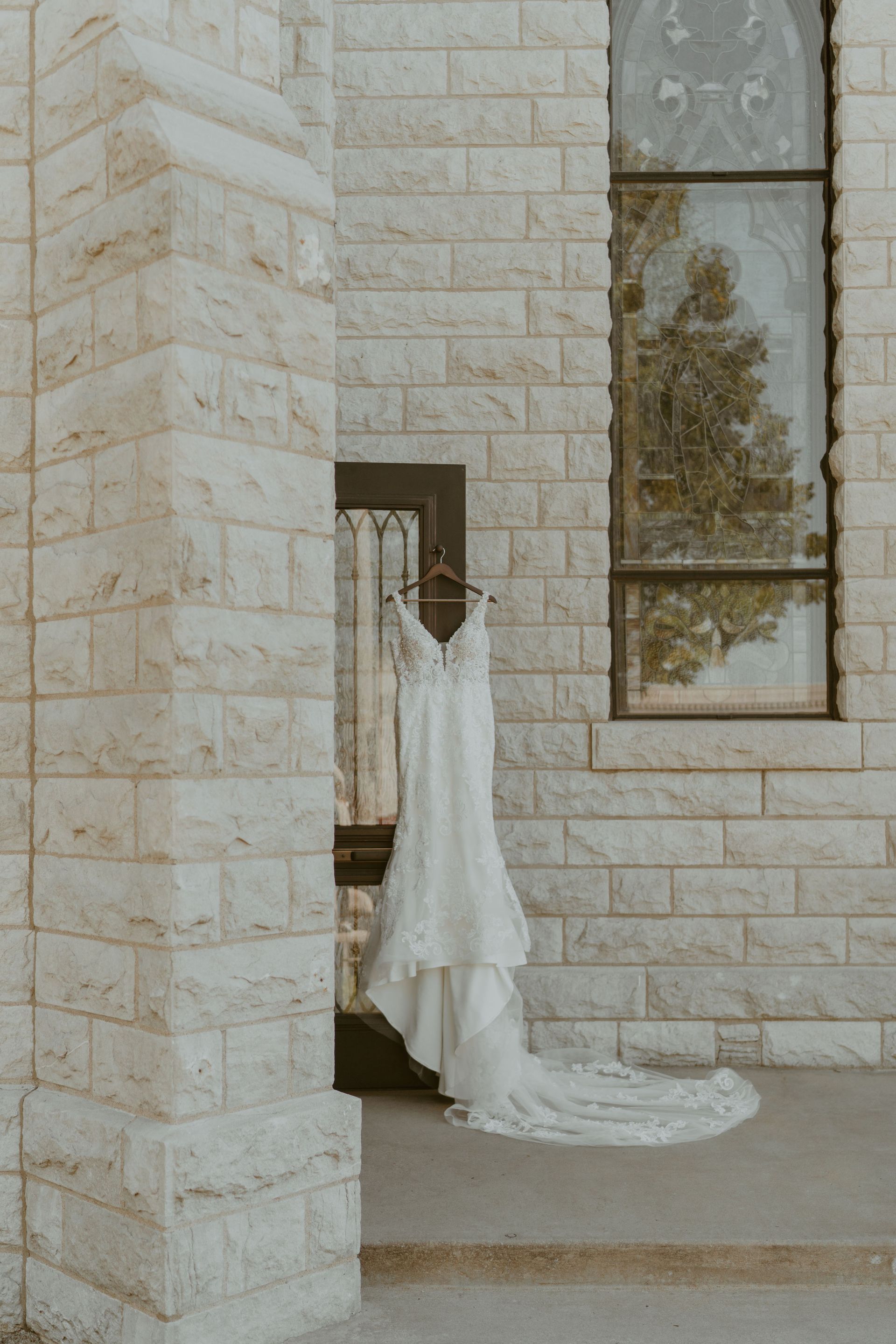 A wedding dress is hanging on a hanger outside of a church.