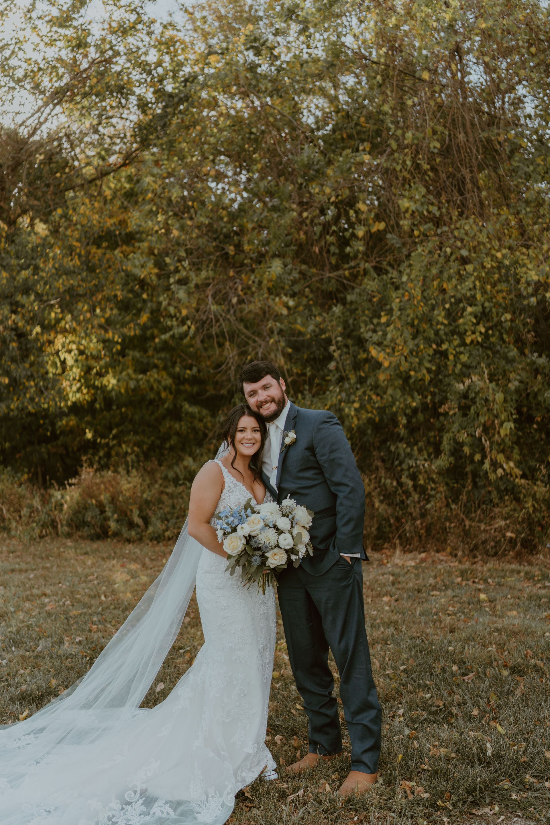 A bride and groom are posing for a picture in a field.