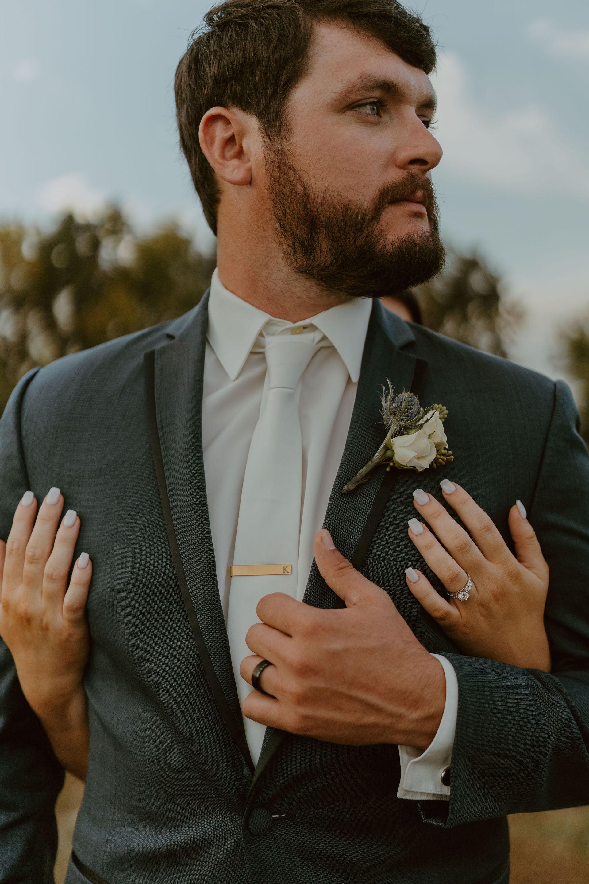 A man in a suit and tie is being hugged by a woman.