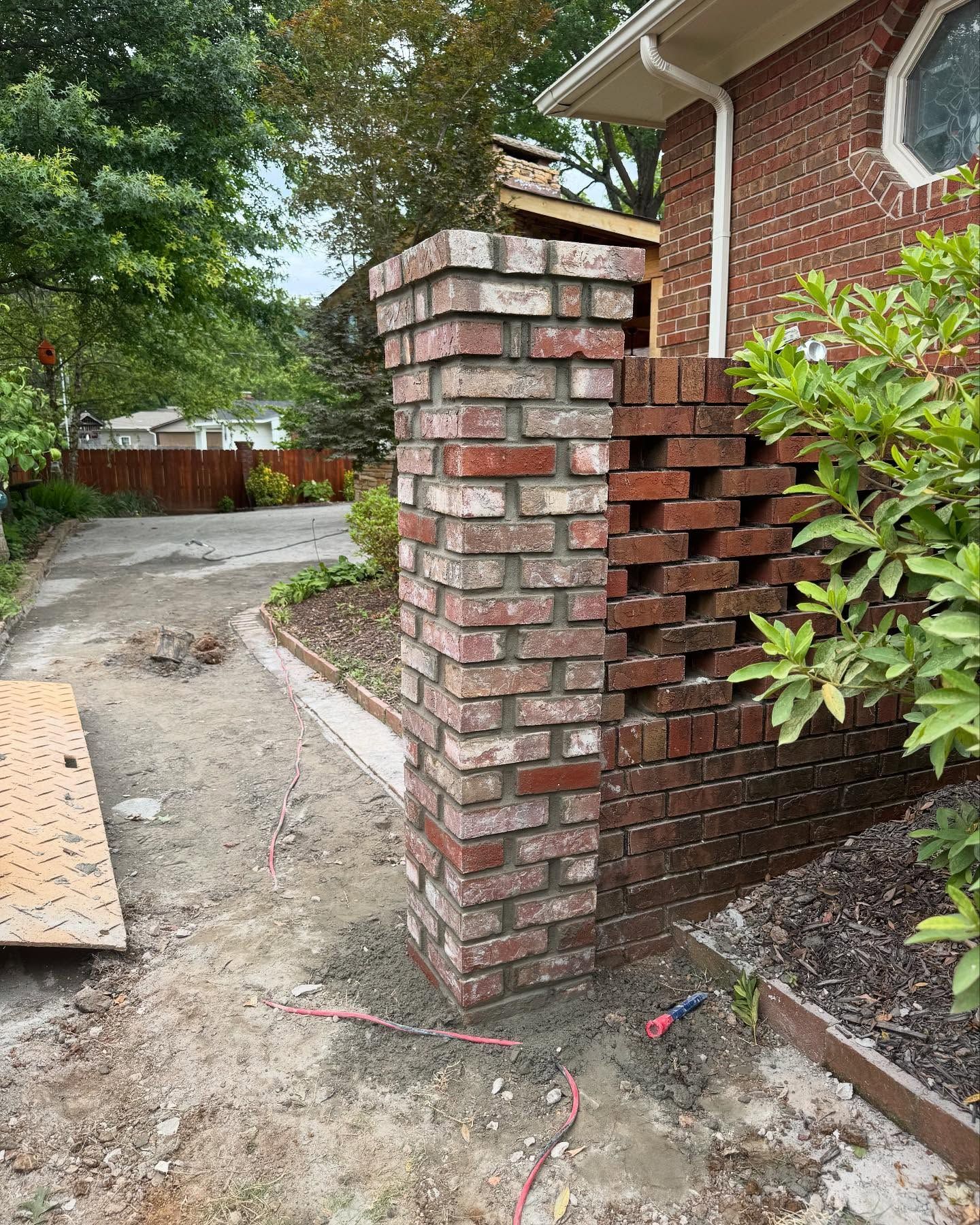 Rock-lined drainage culvert opening in a landscaped yard with gravel paths and grass