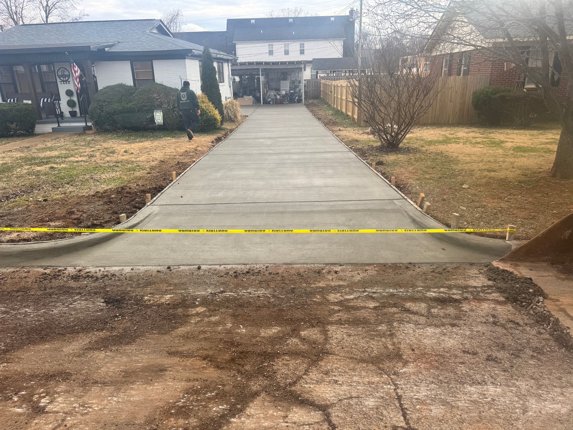 Cracked concrete walkway leading to a house, with yellow caution tape across the entrance.