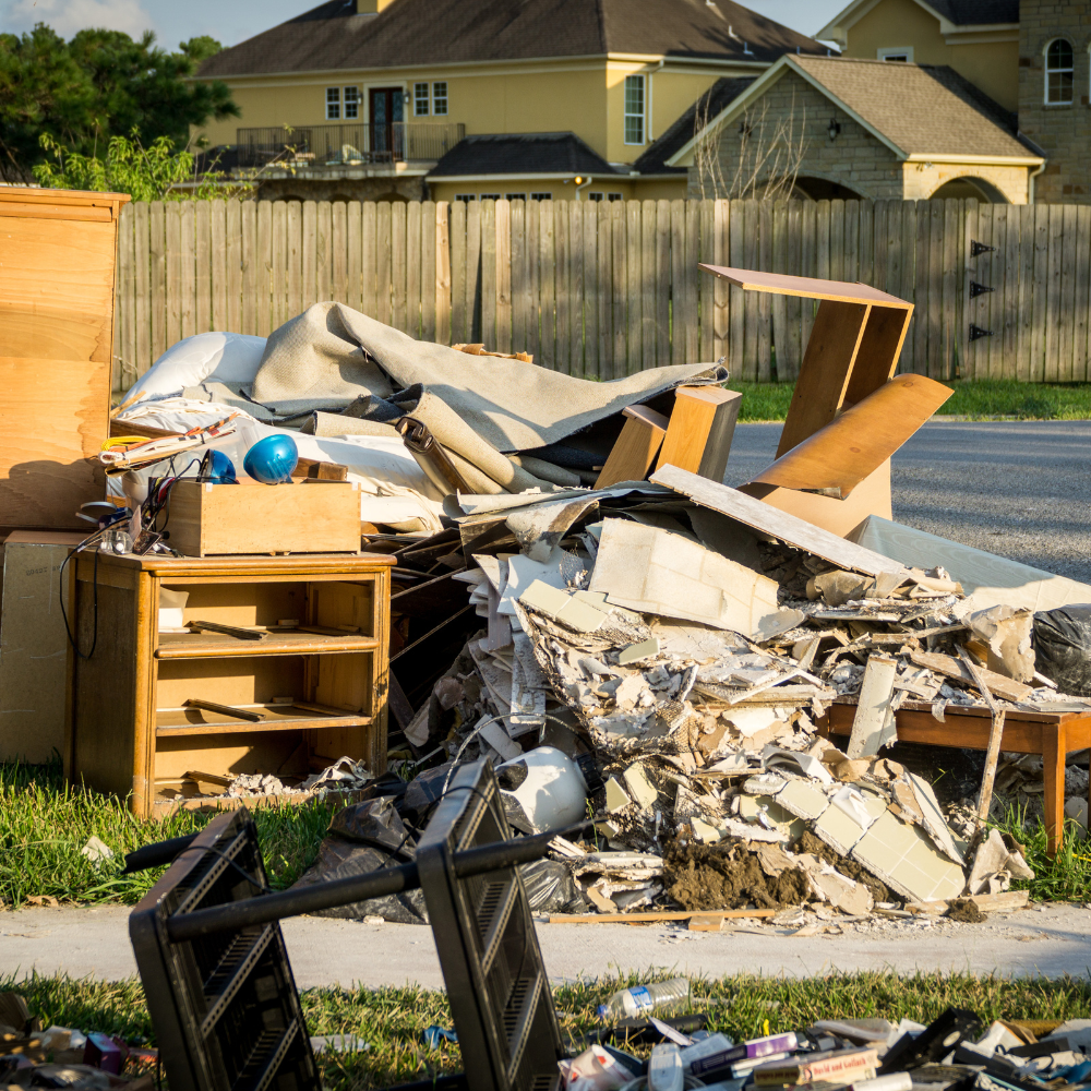 A pile of rubble is sitting on the sidewalk in front of a house
