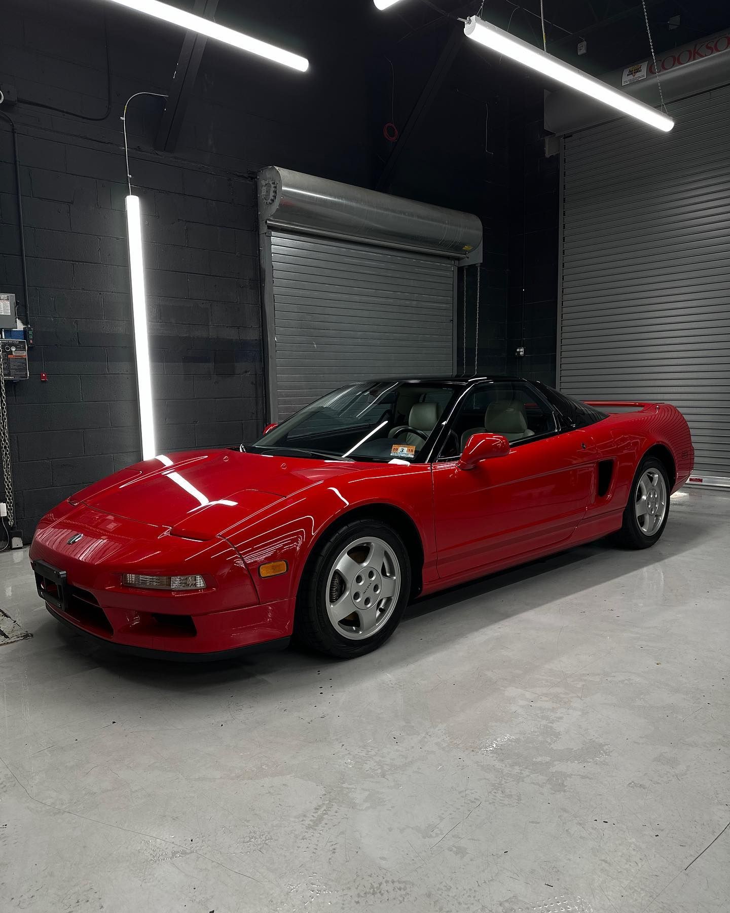 A red sports car is parked in a garage next to a garage door.