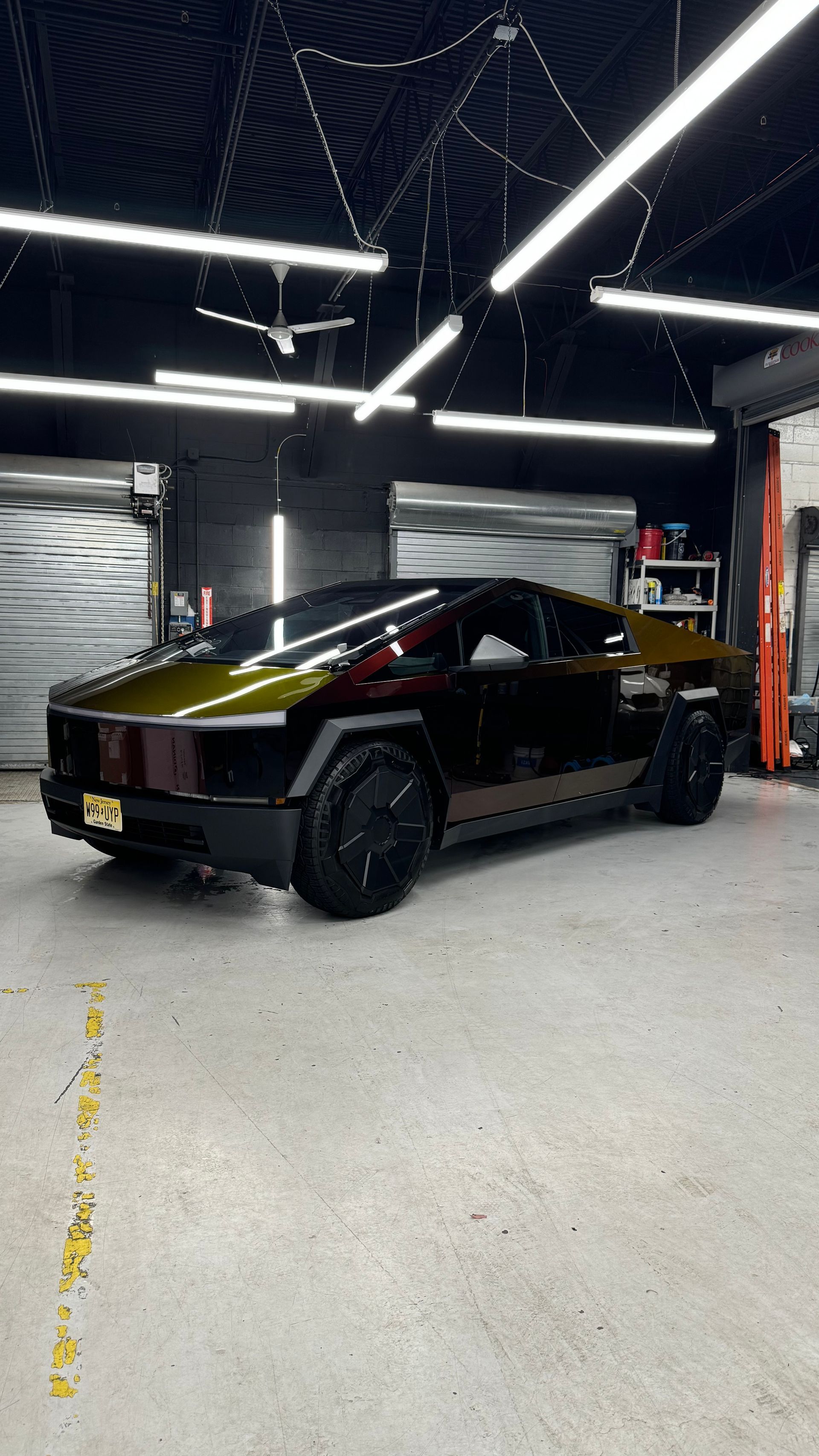 A black and gold tesla model s is parked in a garage.
