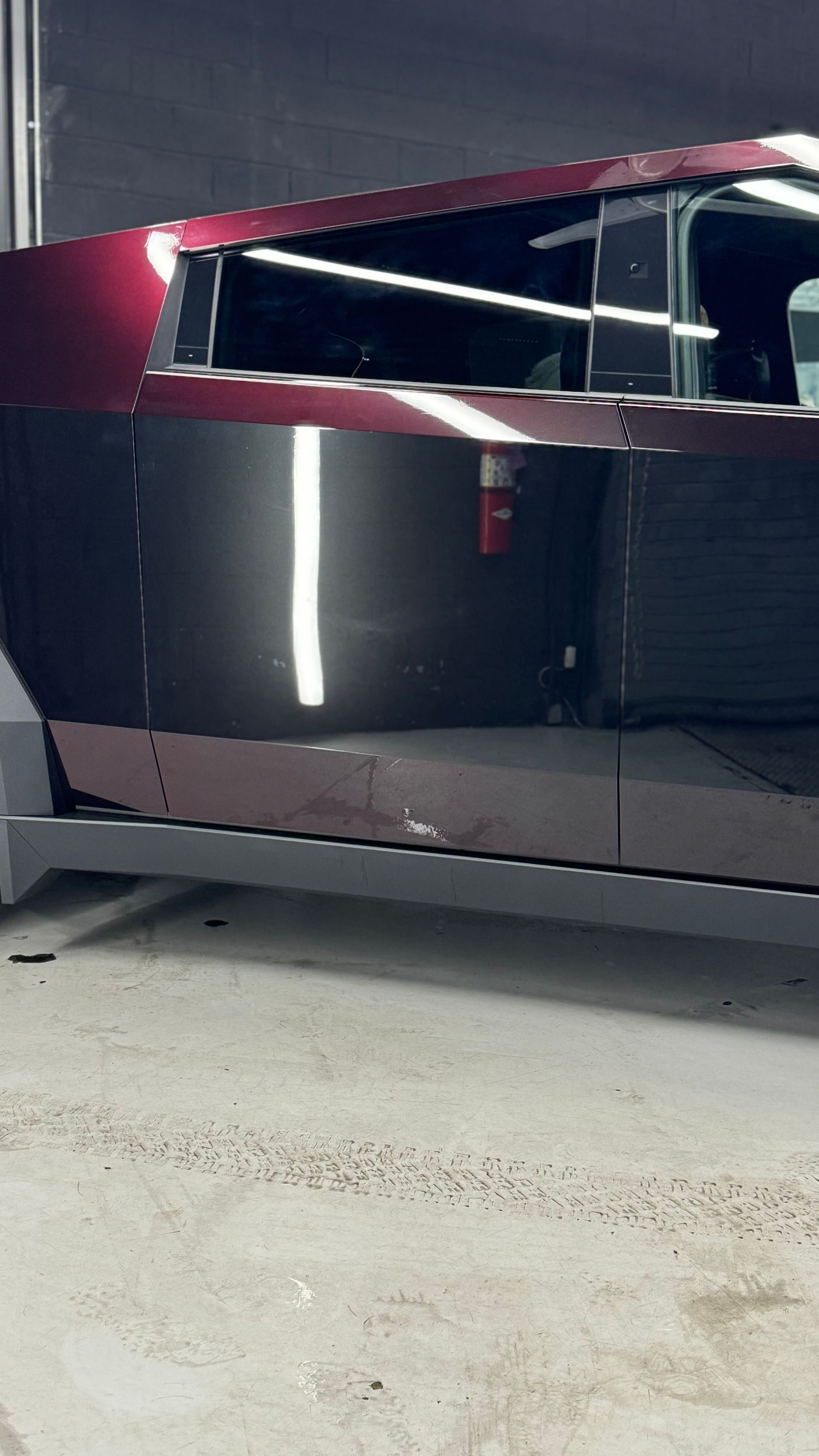A red and black car is parked in a garage.