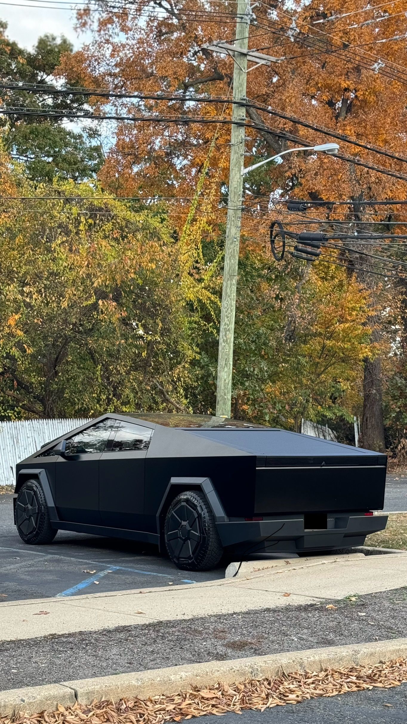 A black tesla cybertruck is parked in a parking lot.