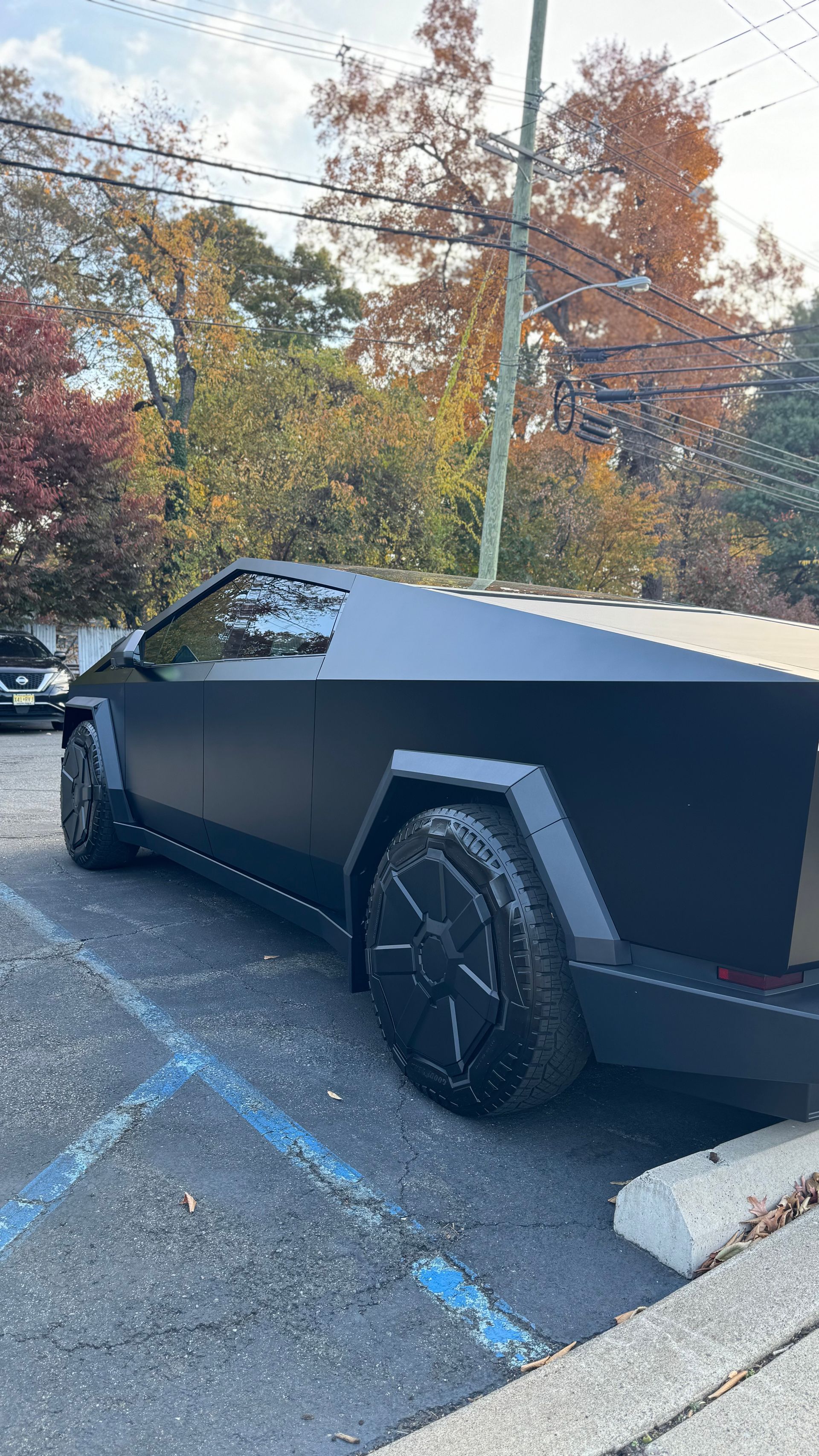 A black tesla cybertruck is parked in a parking lot.