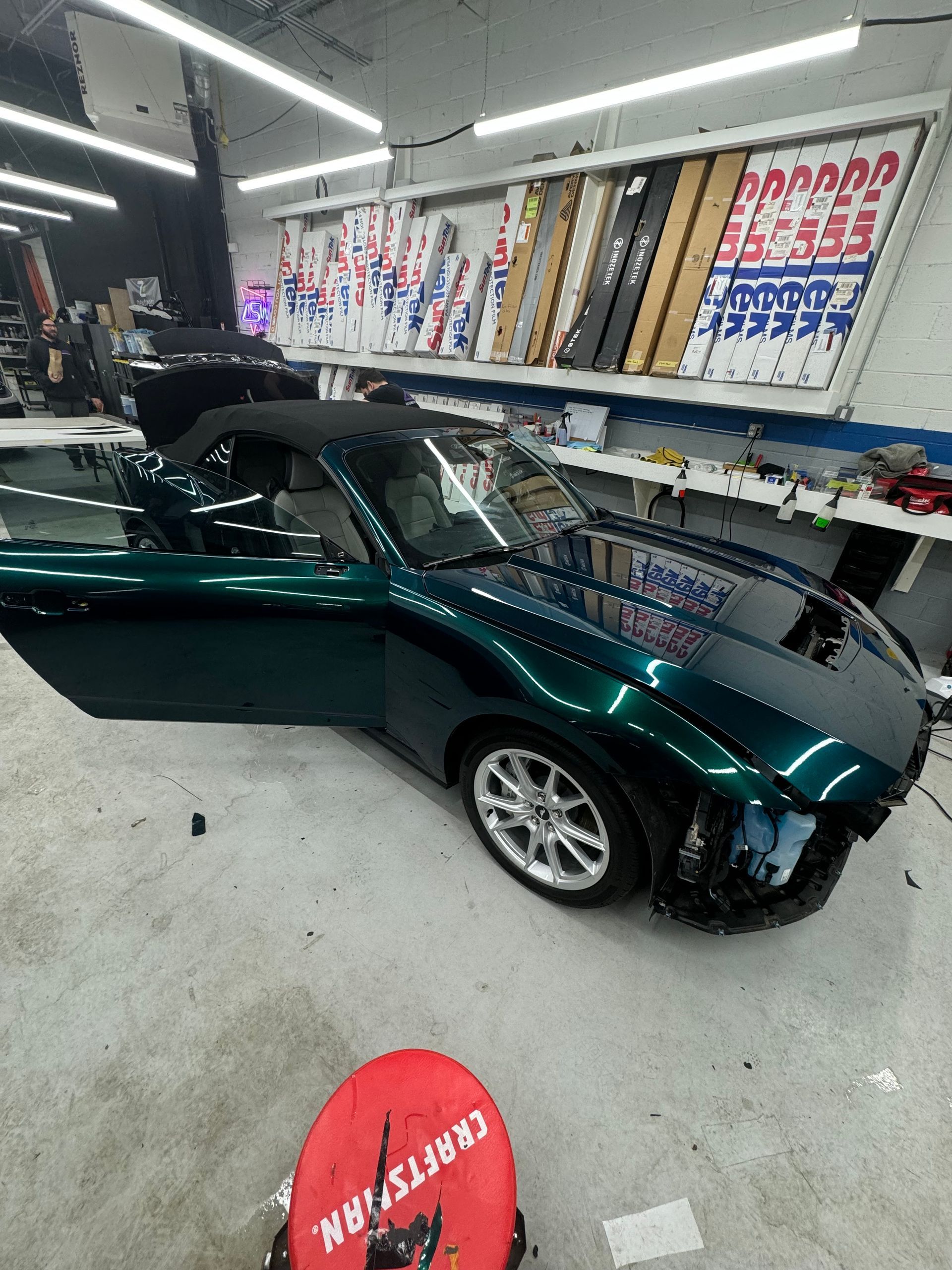 A green car is parked in a garage with its doors open.