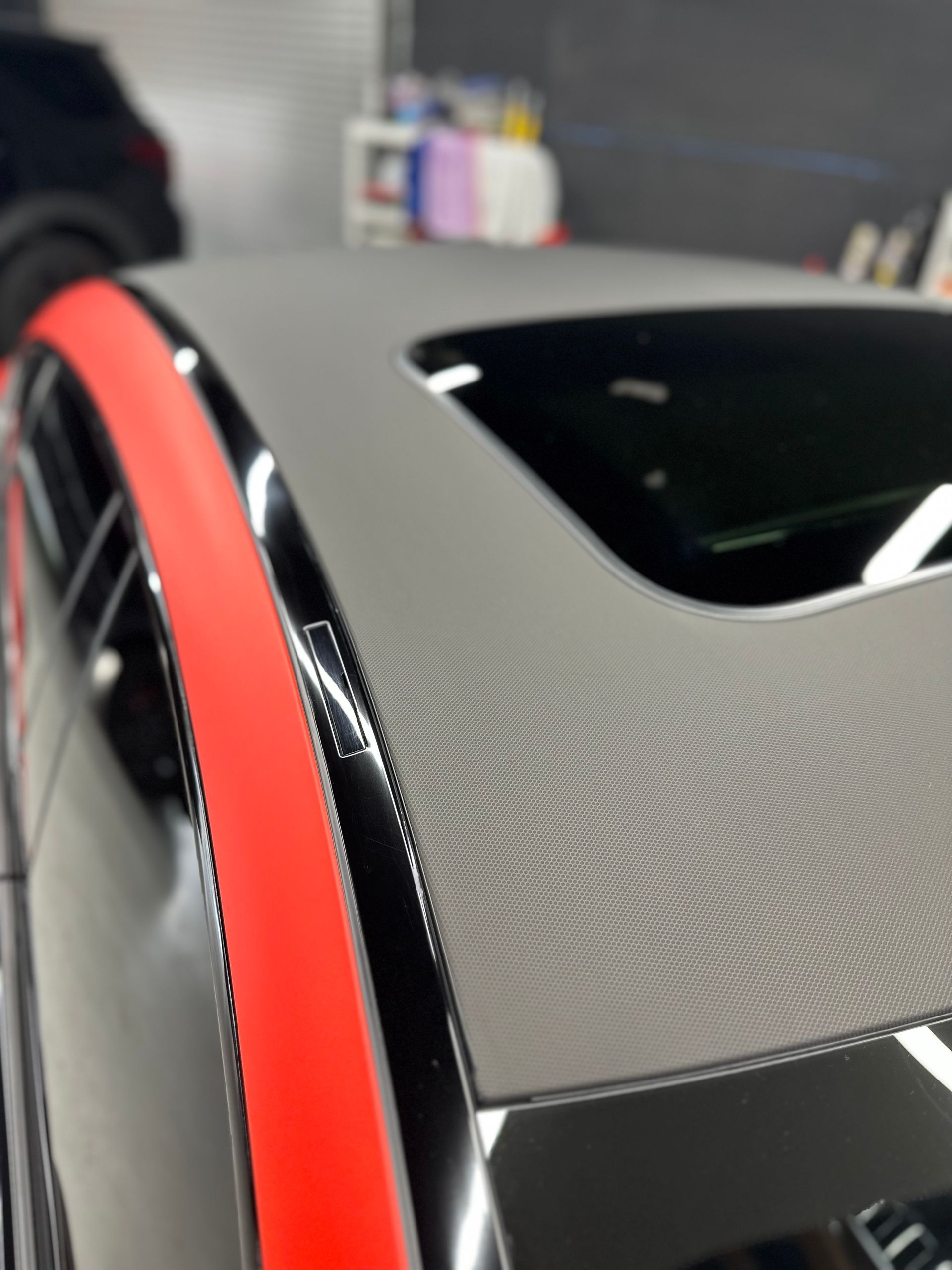 Black car roof with gray textured wrap, red trim, and sunroof.