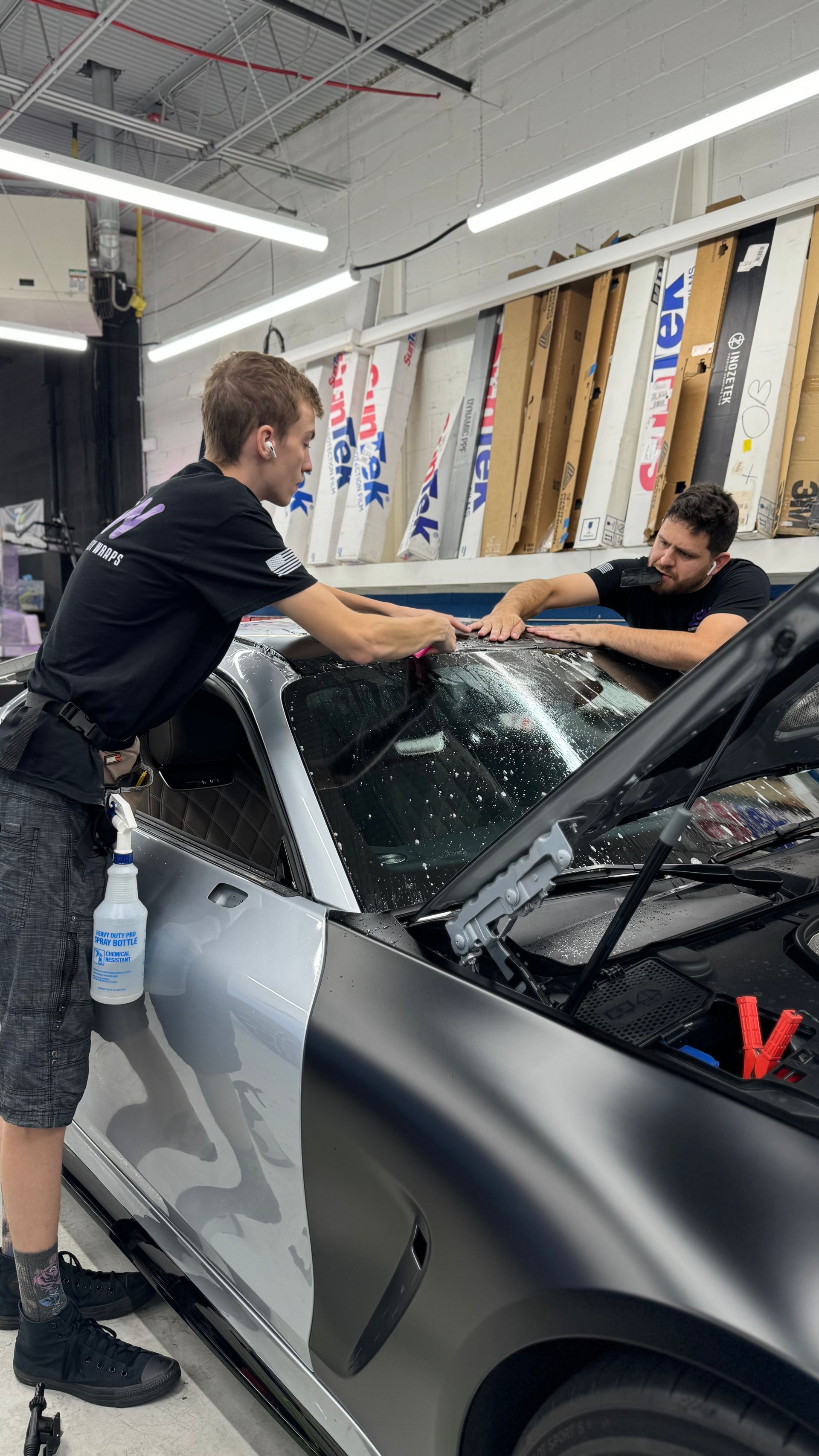 Two men are working on a car in a garage.