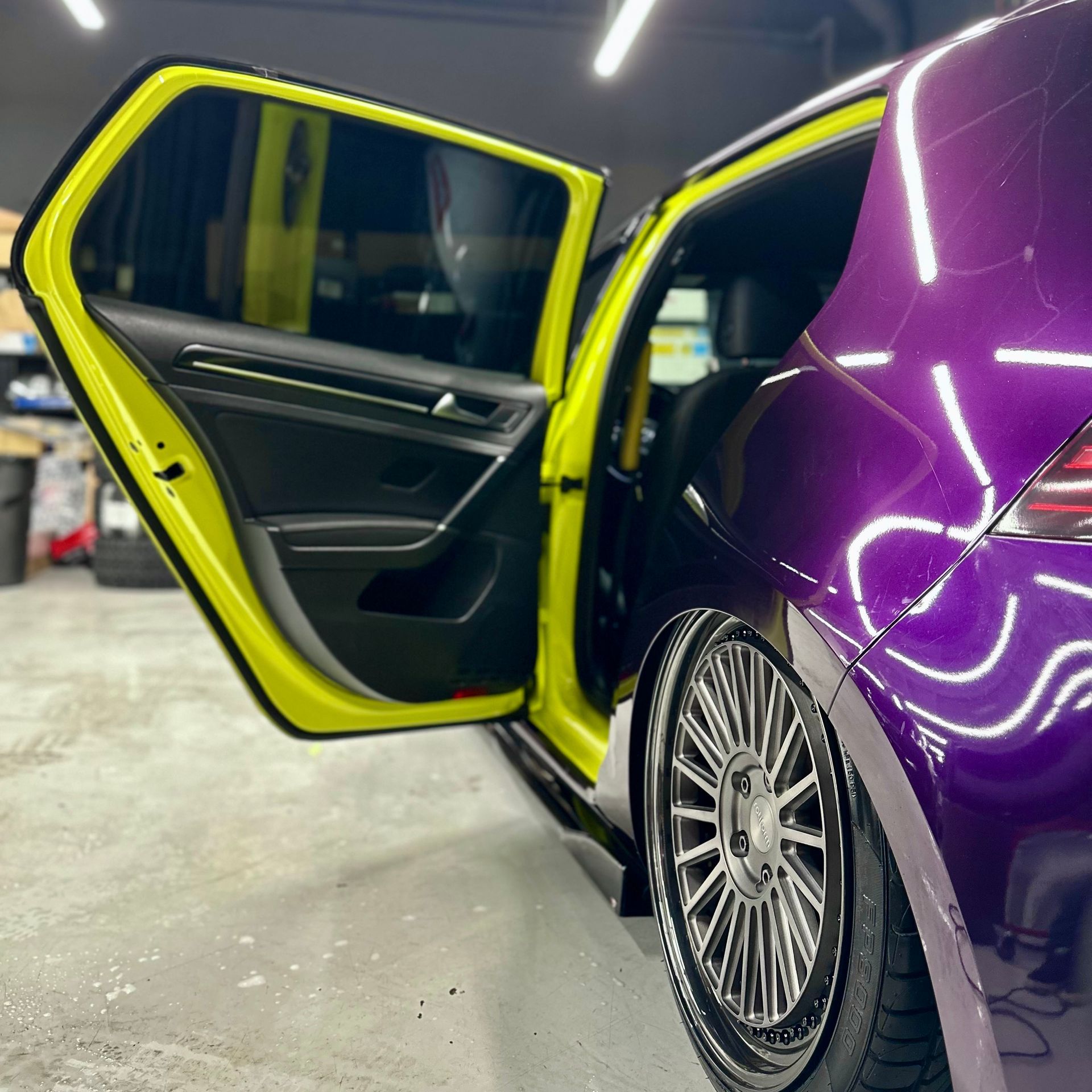 Purple and yellow custom car with open door, showing interior and wheel.