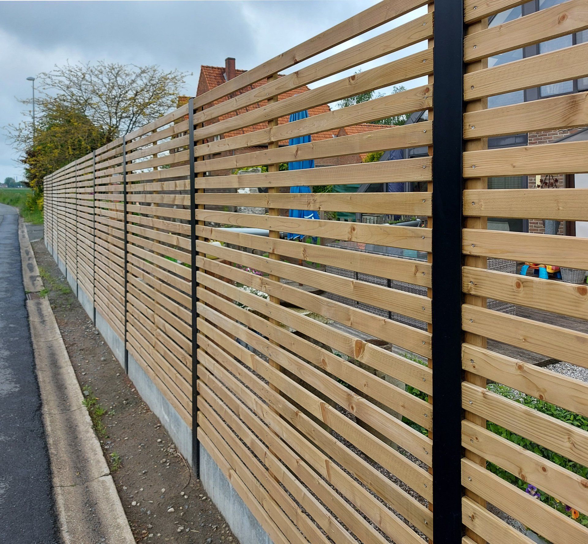 Houten afsluiting met zichtbare zwarte aluminium palen