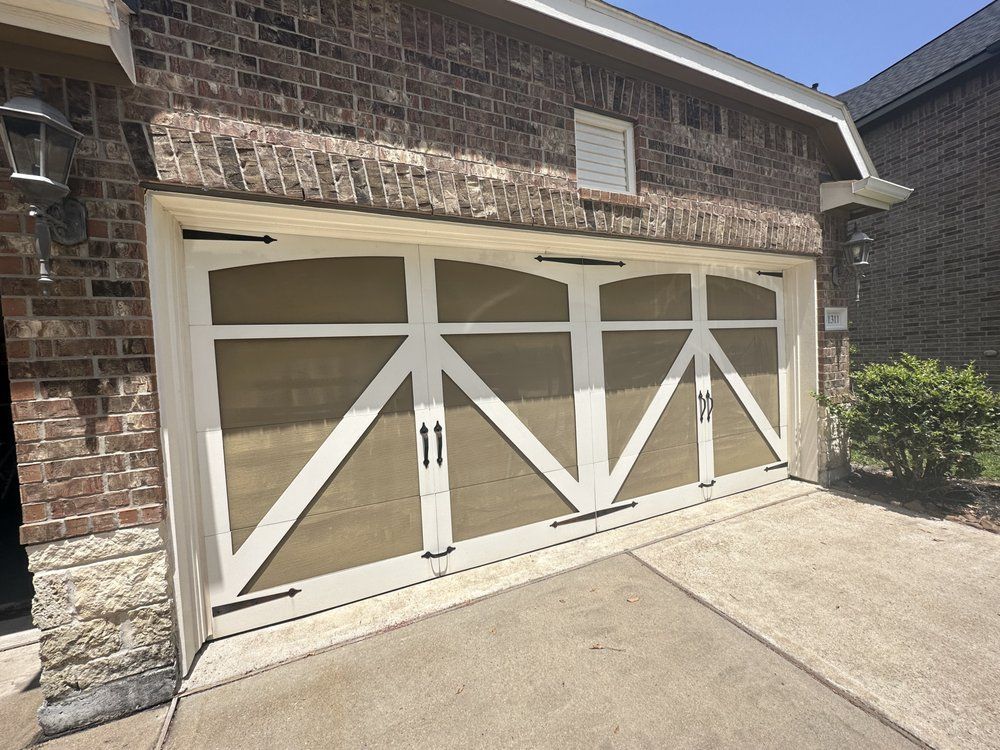 A large white garage door is sitting in front of a brick house.