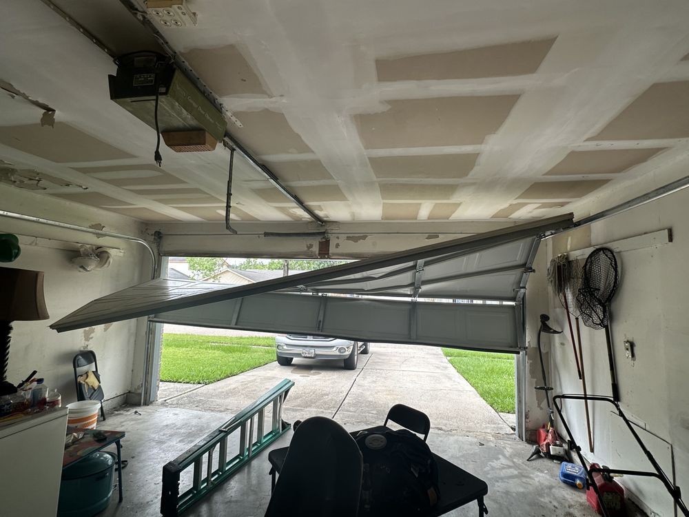 A garage with a broken garage door and a car parked in the driveway.