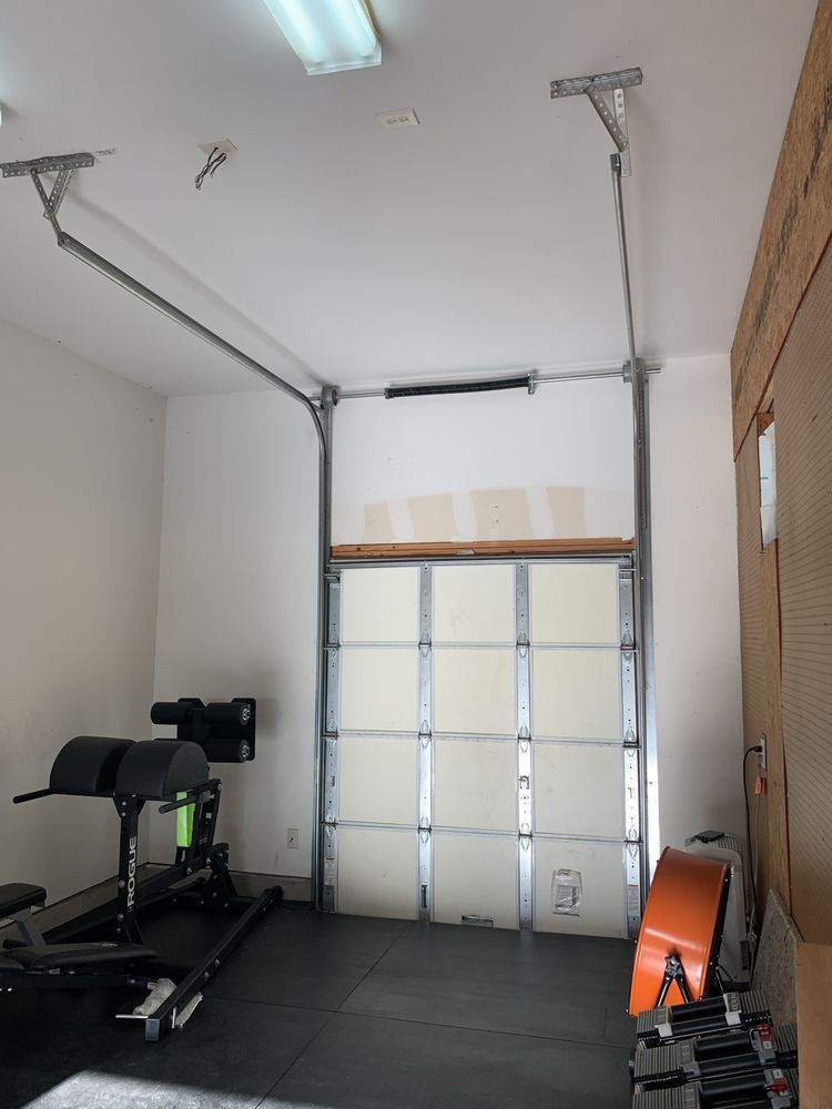 A garage with a gym equipment and a garage door open