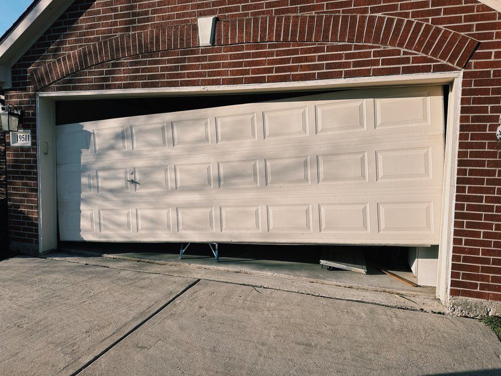 A white garage door is open in front of a brick house