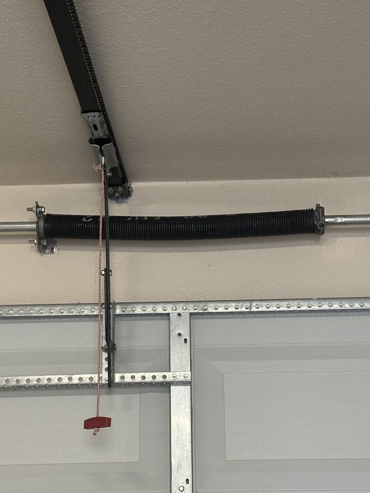 A garage door spring is hanging from the ceiling of a garage.