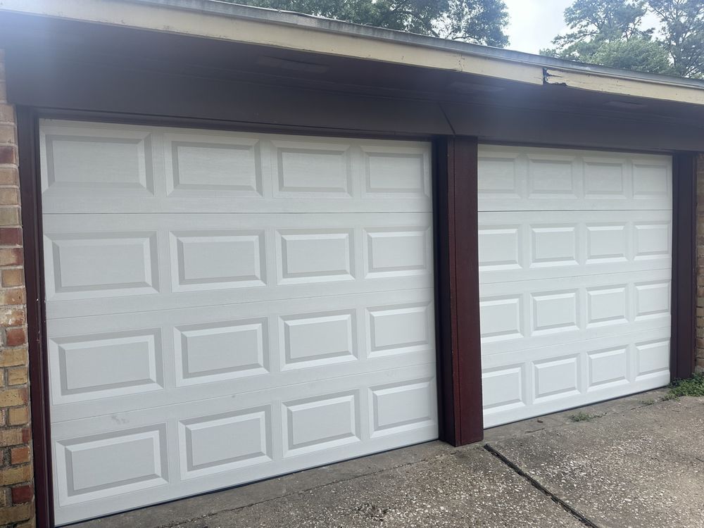 Two white garage doors are sitting next to each other on the side of a house.