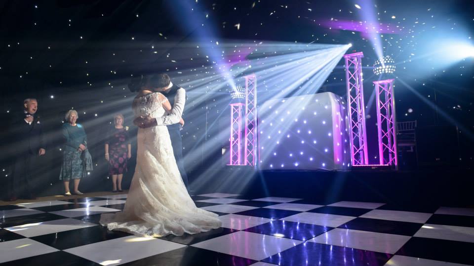 bride and grooms first dance on dance floor with dazzling effect light